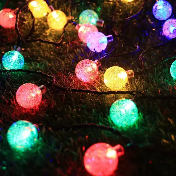 Vibrant multicolored globe lights illuminating grass, showcasing red, green, yellow, and blue bulbs for festive outdoor ambiance