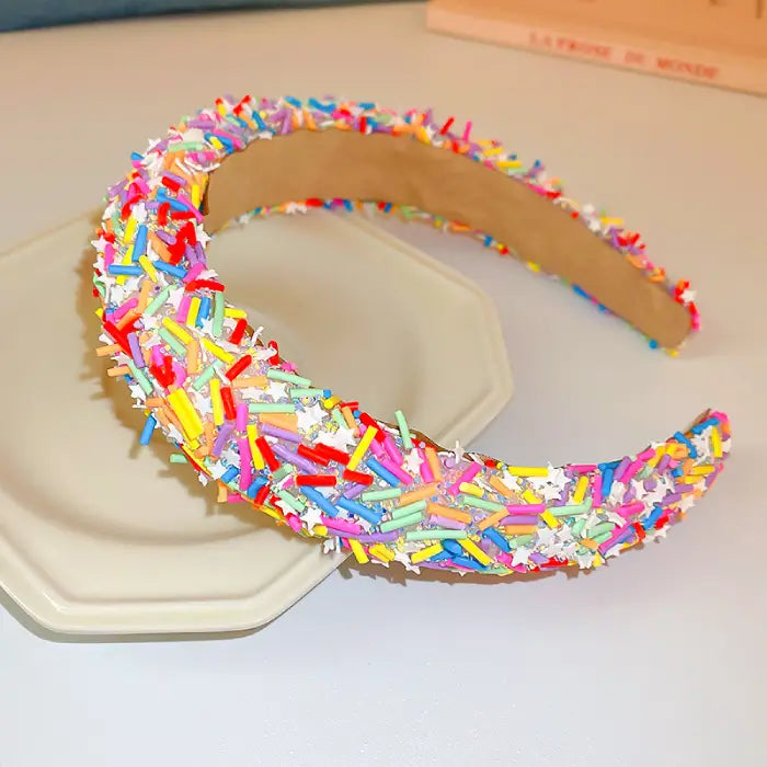 Wide padded headband covered in multicolored candy sprinkle-like texture against cream background