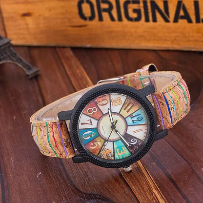 Colorful analog wristwatch with cork strap displayed on a wooden background, highlighting unique craftsmanship.