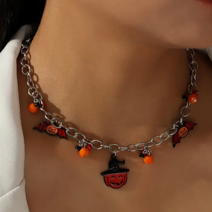 Halloween-themed costume jewelry necklace with pumpkin and bat charms on model's neck.