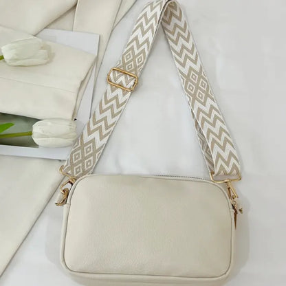 Cream handbag with chevron strap displayed flat, highlighting its minimalistic and elegant design.