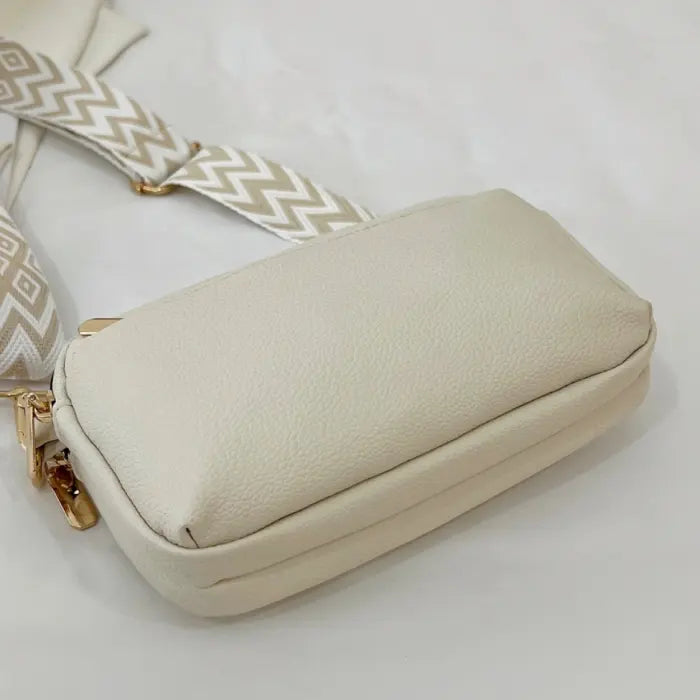 Bottom view of cream crossbody bag with textured leather and stylish chevron strap accents.