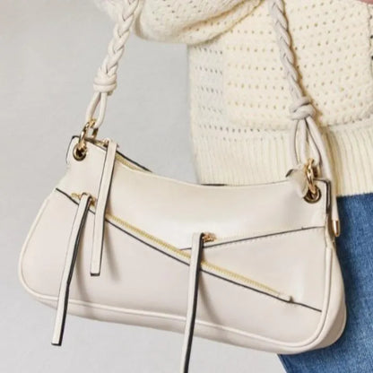 Cream leather handbag with braided handle and gold accents styled with cream cardigan for casual everyday look