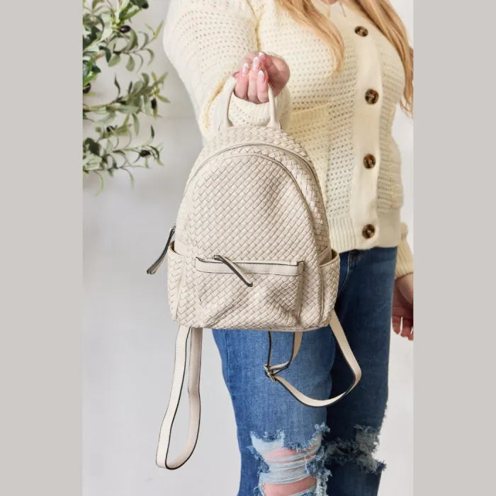 Close-up of cream woven leather backpack held by a woman, highlighting texture and strap details.