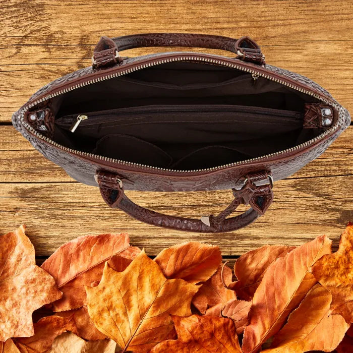 Crocodile embossed handbag interior with zipper pockets and compartments, shown on autumn wood surface.