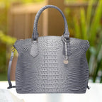 Crocodile embossed handbag in steel grey with classic top handle design and structured build, outdoors.