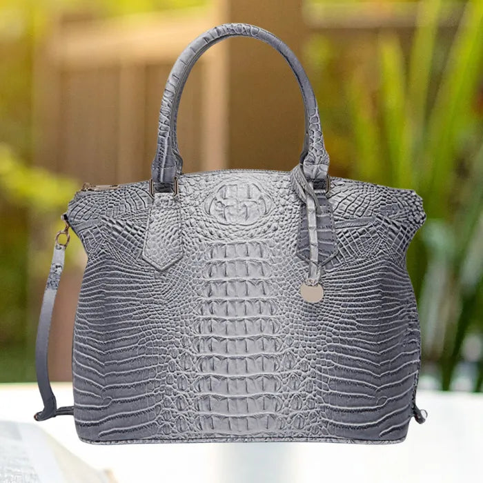 Crocodile embossed handbag in steel grey with classic top handle design and structured build, outdoors.