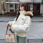 Cropped bomber jacket with fur hood in cream color, styled outdoors showing padded winter warmth and fashionable fit