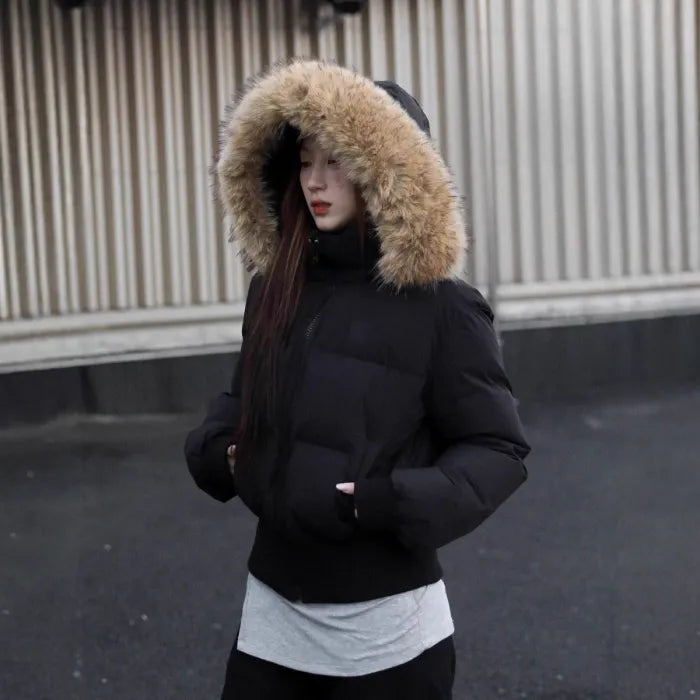 Cropped bomber jacket with fur hood shown in side profile, winter puffer silhouette emphasizing warmth and relaxed fit