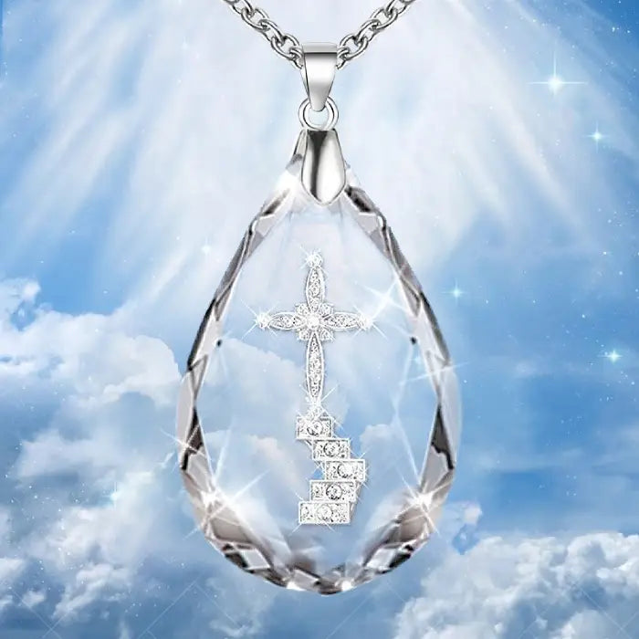 Sparkling crystal cross pendant necklace with radiant blue sky and heavenly light background.