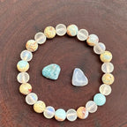 Crystal healing bracelet with jasper and frosted beads beside raw stones, enhancing grounding energy and emotional restoration