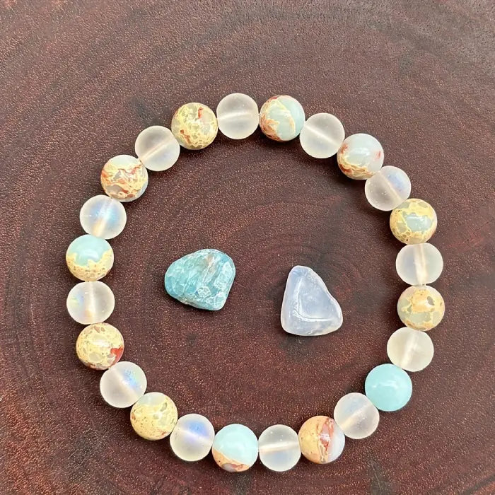Crystal healing bracelet with jasper and frosted beads beside raw stones, enhancing grounding energy and emotional restoration