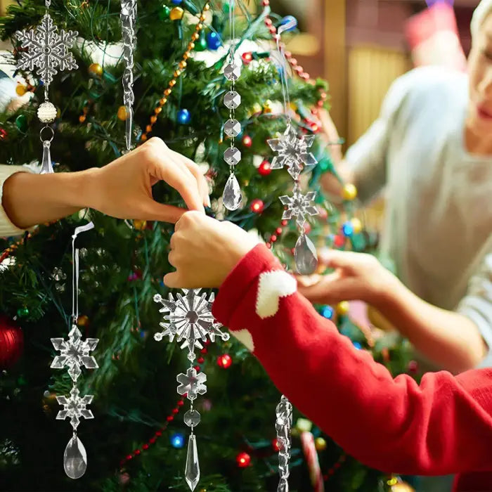  Person decorating Christmas tree with crystal snowflake ornaments and icicle drops, showing installation process