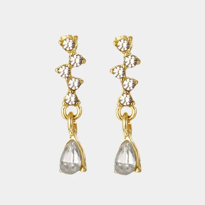 crystal teardrop dangle earrings in gold isolated on white, sparkling rhinestone drops creating a dainty elegant accessory for women