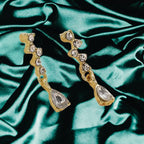 crystal teardrop dangle earrings in gold styled on emerald satin fabric, sparkling rhinestone drops offering a luxe elegant accessory feel