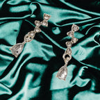 crystal teardrop dangle earrings in silver displayed on emerald satin backdrop, shimmering stones creating an elegant refined jewelry look