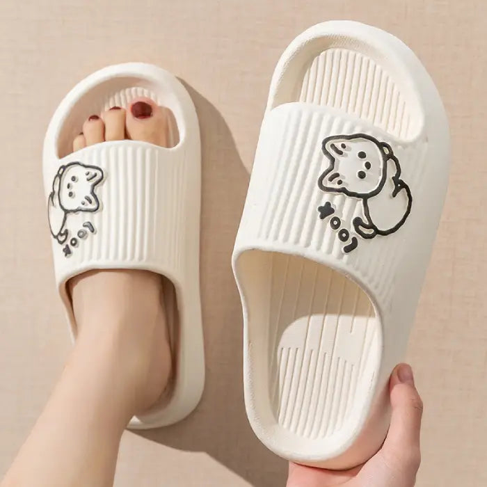 White bathroom slides with ribbed texture and adorable cartoon cat design shown on feet with painted toenails