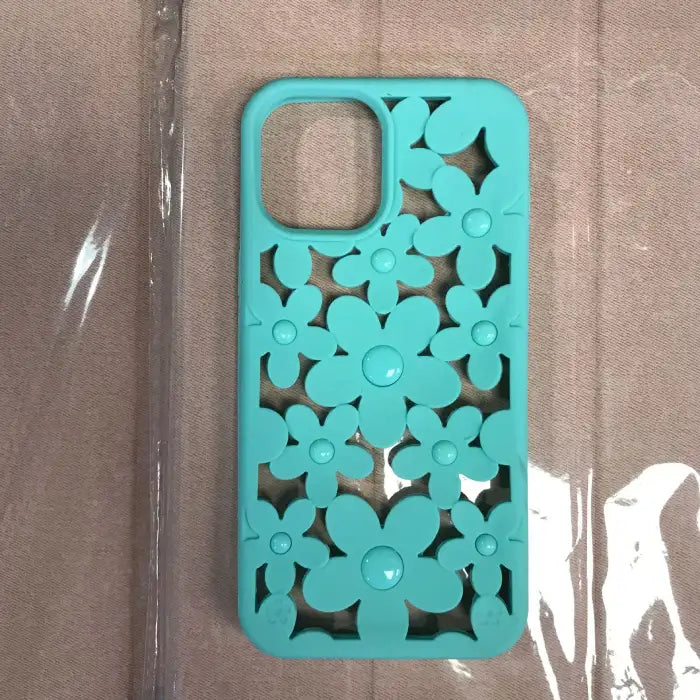 Cute floral iPhone case in turquoise with 3D flower cutout pattern featuring raised button centers on neutral background