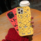 Cute floral iPhone case in yellow and coral colors with 3D daisy cutout design displayed on wooden table