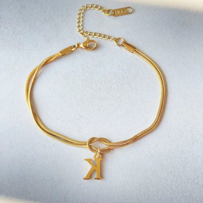 Gold bracelet with a 'K' charm on a light gray background