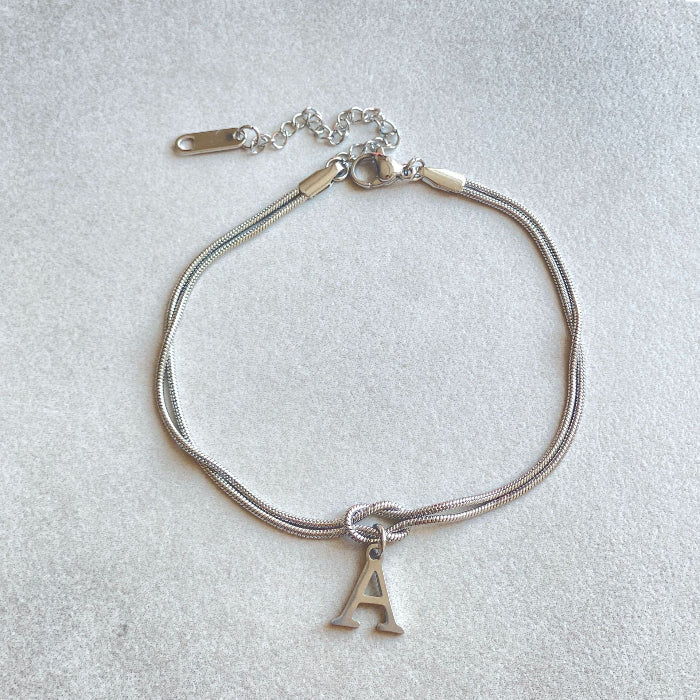 Silver bracelet with a letter 'A' charm on a light gray background