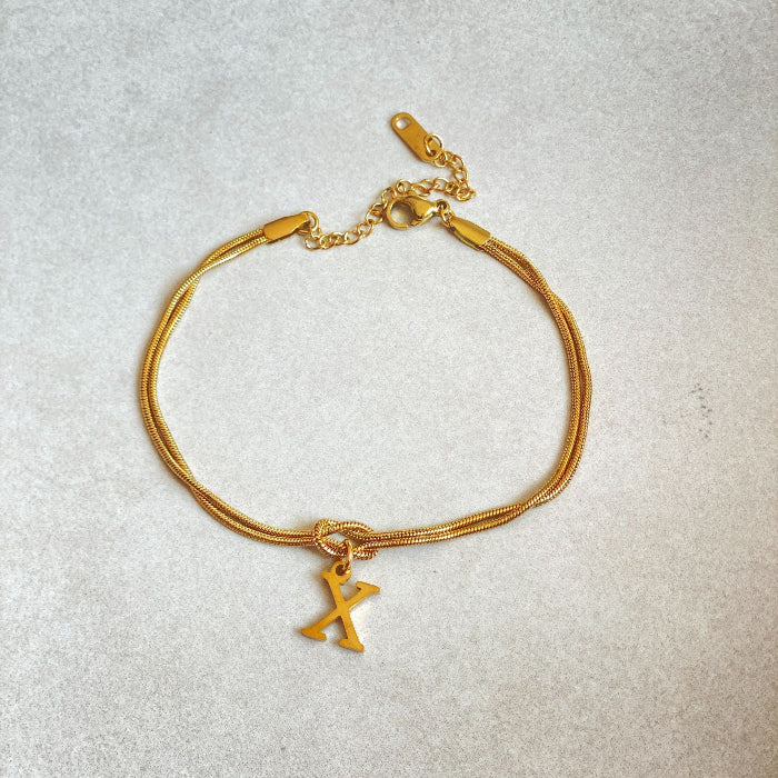 Gold bracelet with a unique charm on a light gray background