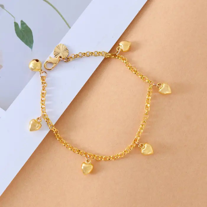 dainty gold heart chain bracelet with small dangling charms displayed on soft background, offering an elegant minimalist gift-ready style
