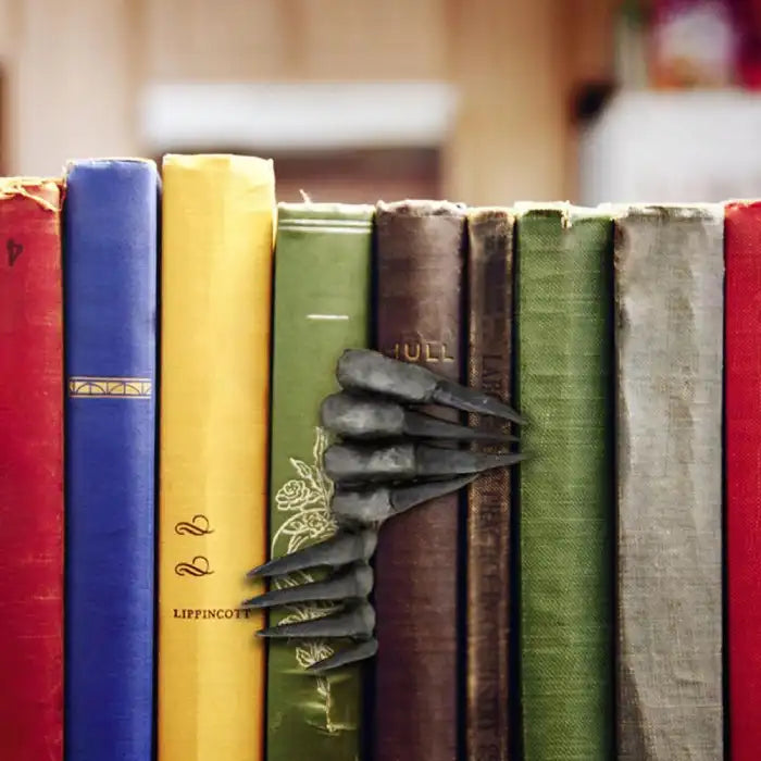 Decorative sculpture with black claw design seen on a shelf between vintage books in cozy room.