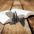 Decorative sculpture bookmark shaped like dinosaur hand placed inside open book on wood floor.