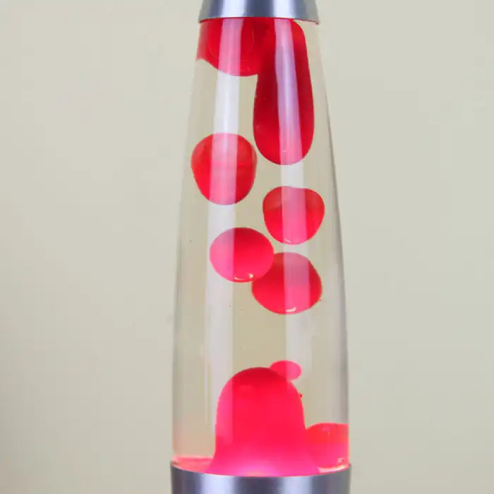 Decorative wax lamp closeup showing red wax blobs in a tall clear glass with silver base.