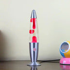 Decorative wax lamp with red wax in a silver base on a desk beside a colorful mini fan.