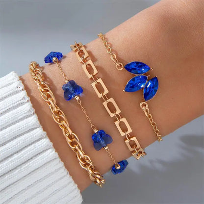 Delicate gold bracelets featuring blue gemstones with floral and geometric designs for elegant styling.