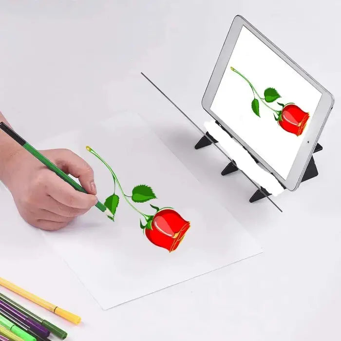 Hand drawing red rose on paper with green pencil, mirroring image on digital tablet display, colored pencils in foreground