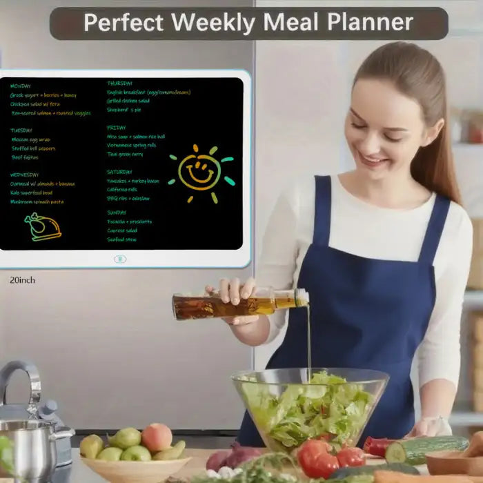 Drawing tablet used as a weekly meal planner on kitchen wall beside woman preparing a salad.