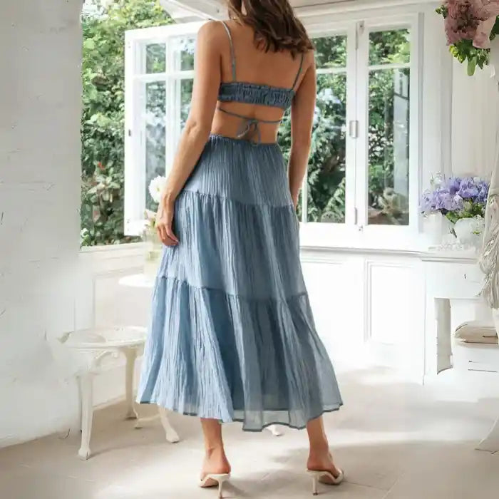Dress in blue with open back and tiered midi skirt in a breezy style