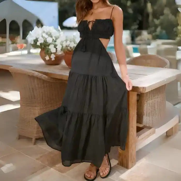 Dress in black with cinched bust, side cutouts, and tiered flowy skirt