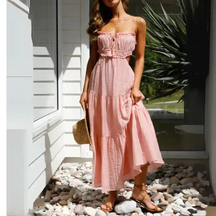 Dress in light pink with tie front, tiered skirt and flowy fabric styled for vacation wear