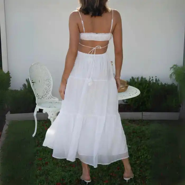 Dress in white with back tie straps and tiered flowing skirt, seen from behind.