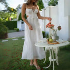 Dress in breezy white with cutouts styled outdoors beside table with flowers and fruit.