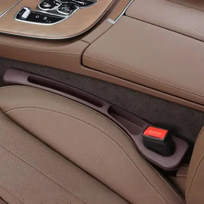 Driver side brown plastic car seat gap filler installed between brown leather seats with chrome console trim