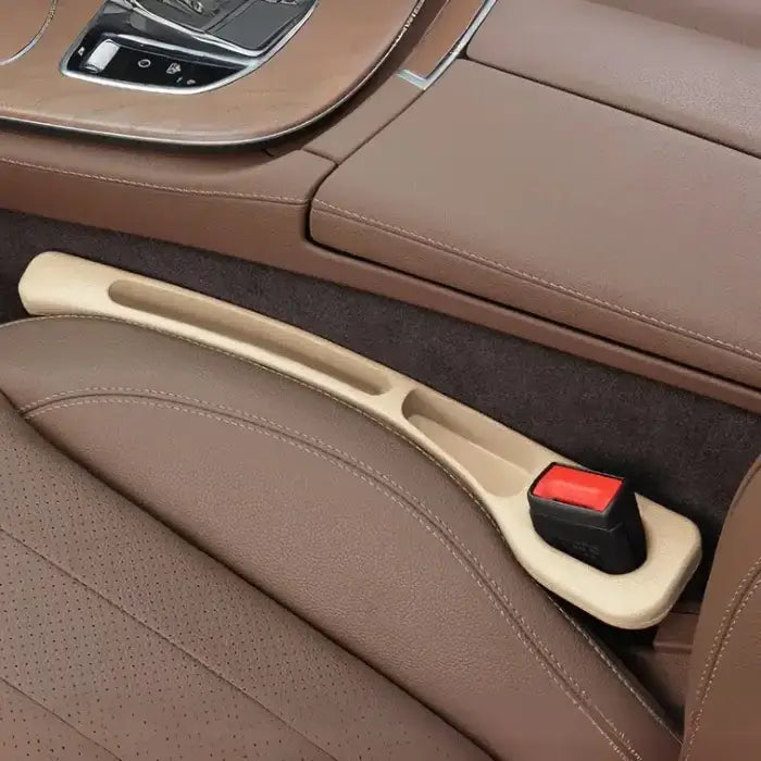 Driver side beige plastic car seat gap filler installed between brown leather seats with chrome console trim