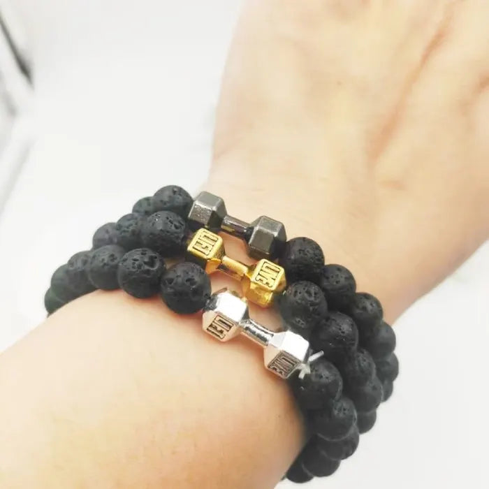 stacked dumbbell bracelets with gold silver and gunmetal charms worn on wrist
