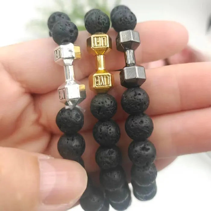 three dumbbell bracelets with lava beads and silver gold gunmetal charms held in hand
