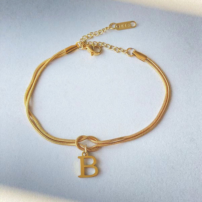 Gold bracelet with a letter 'B' charm on a light gray background