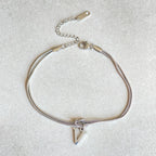 Silver bracelet with a triangle charm on a light gray background