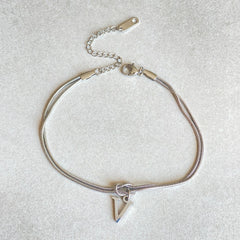 Silver bracelet with a triangle charm on a light gray background