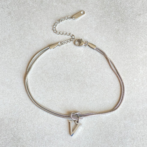 Silver bracelet with a triangle charm on a light gray background