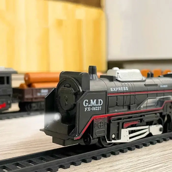 Close-up of electric locomotive toy train with glowing headlights and cargo cars in the background.