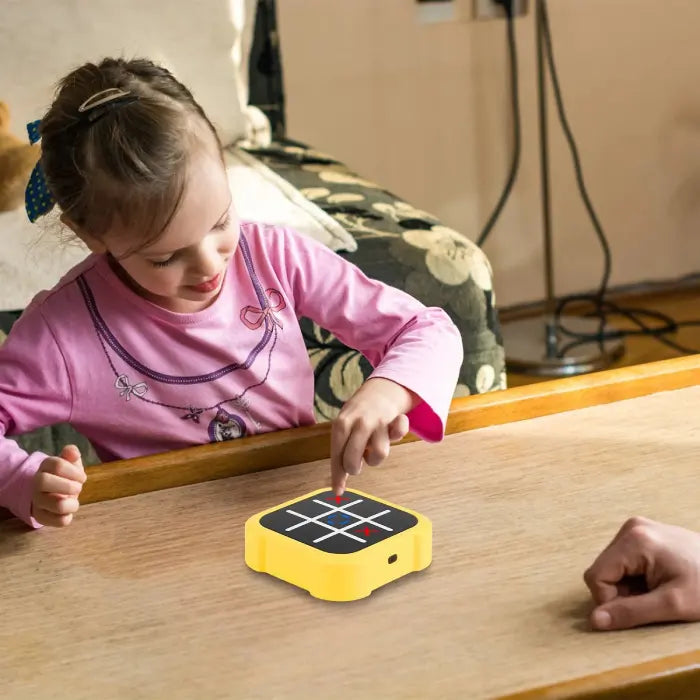 Child playing with Electronic Tic-Tac-Toe Game on a wooden table indoors.