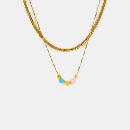 A delicate golden necklace with three heart-shaped pendants in blue, yellow, and pink colors on a plain white background